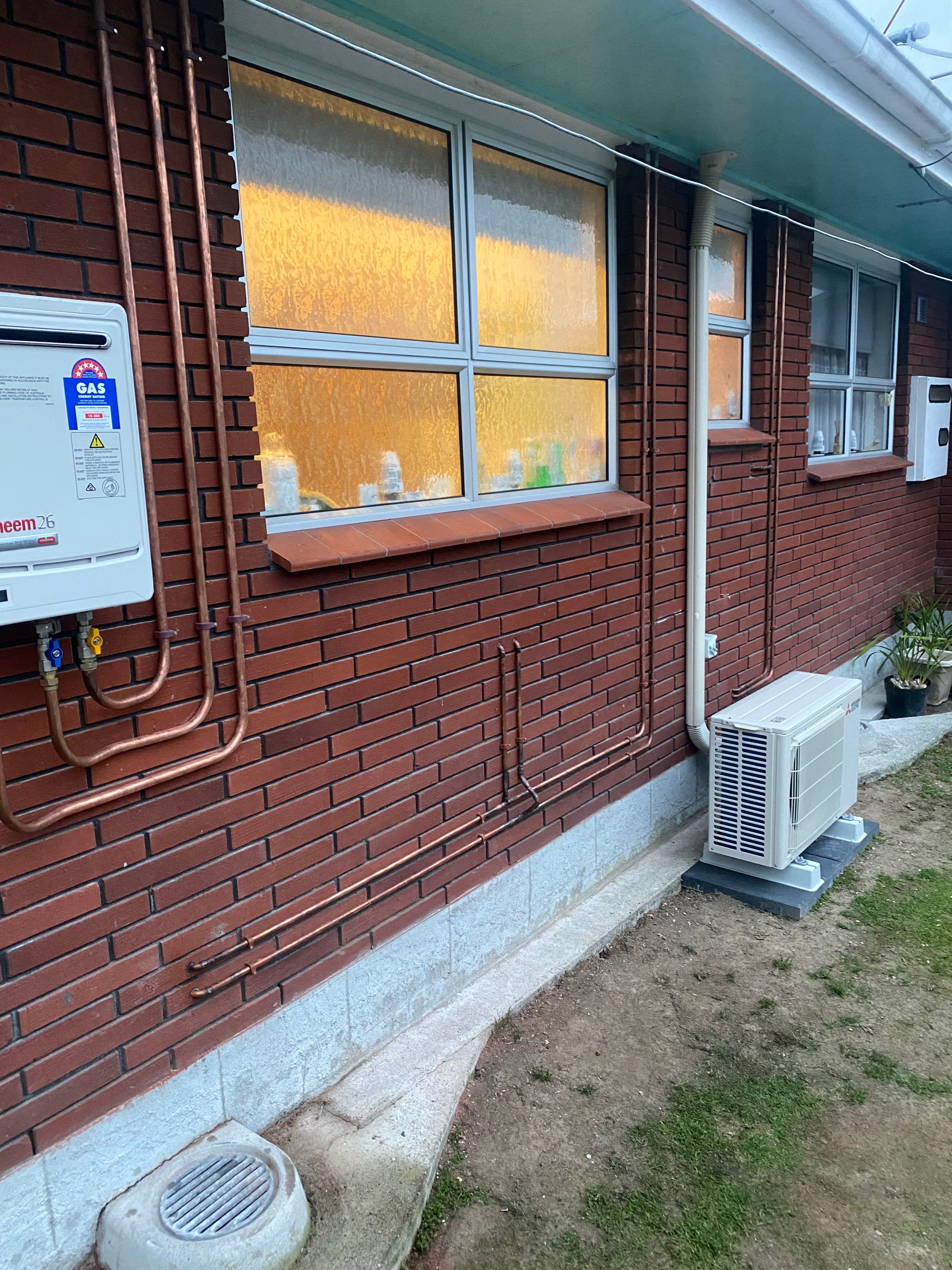 Gas fitting installation showing copper lines on brick exterior